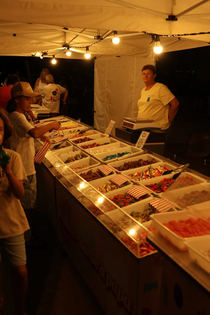 Stand de confiseries éclairé à la nuit tombante, O’Mazette 2026